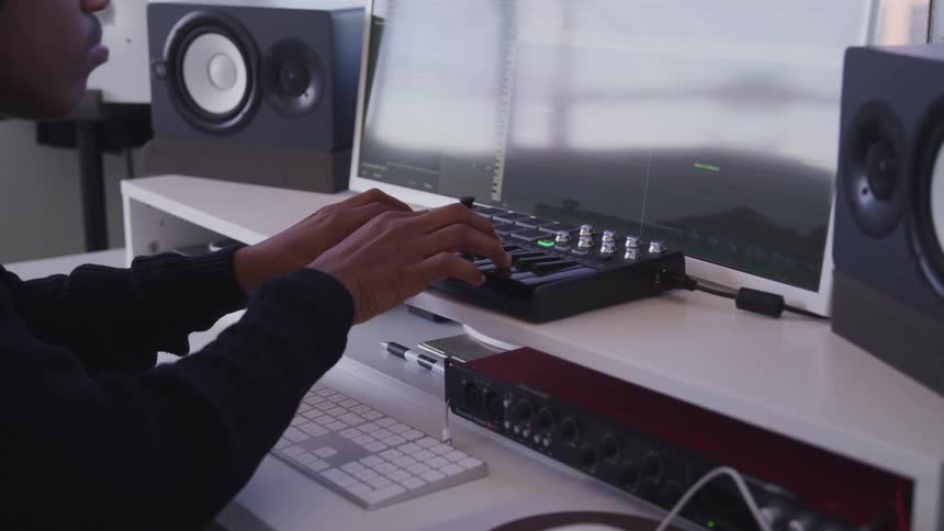 A man makes and records music while sitting at his desk