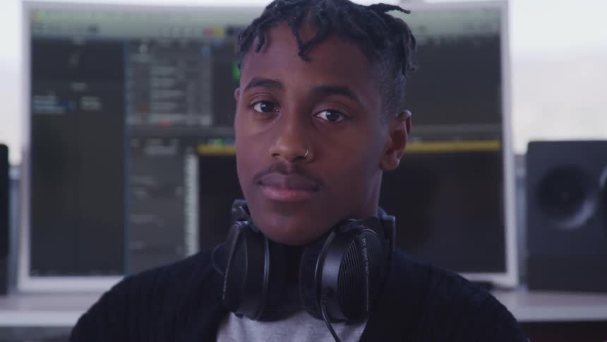 Black man in an audio studio with headphones around his neck