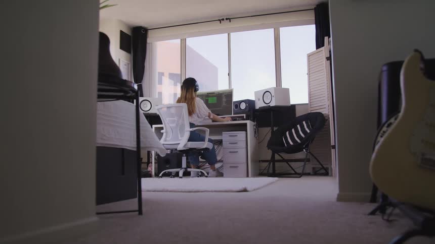 Woman wearing headphones works on a computer in a music studio