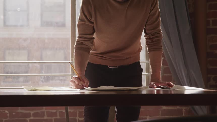 A man is standing in a room and writing on paper