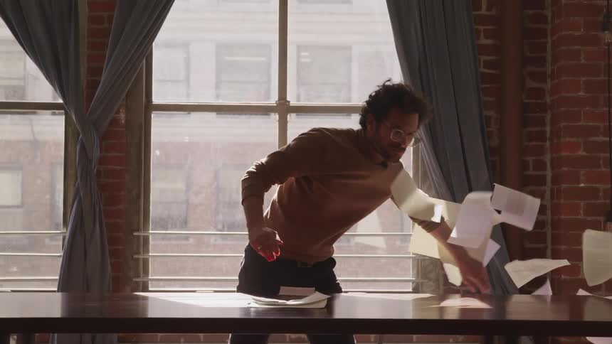 A man throws all of his papers on the ground in a rage