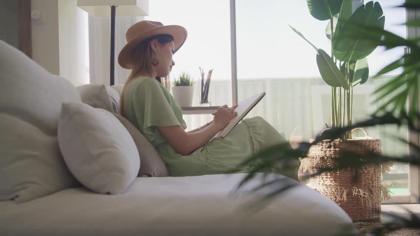 A woman sits at home sketching