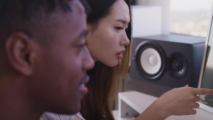 Couple of composers use a computer to edit music in a studio