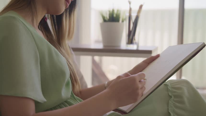 A woman sitting with a notepad and a pencil drawing