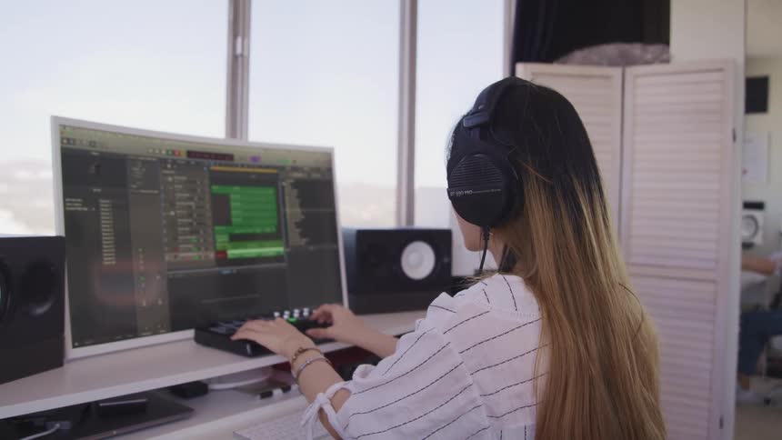 Woman works with audio equipment and computer near window showing urban sprawl