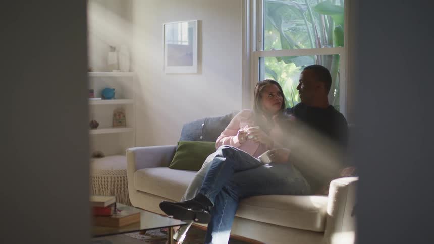 A man and woman sit closely together on a couch
