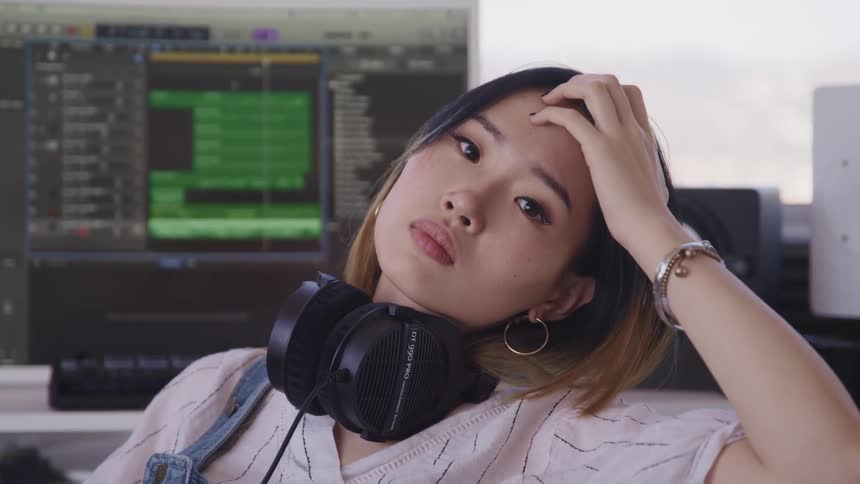 A woman wearing headphones brushes her hair back