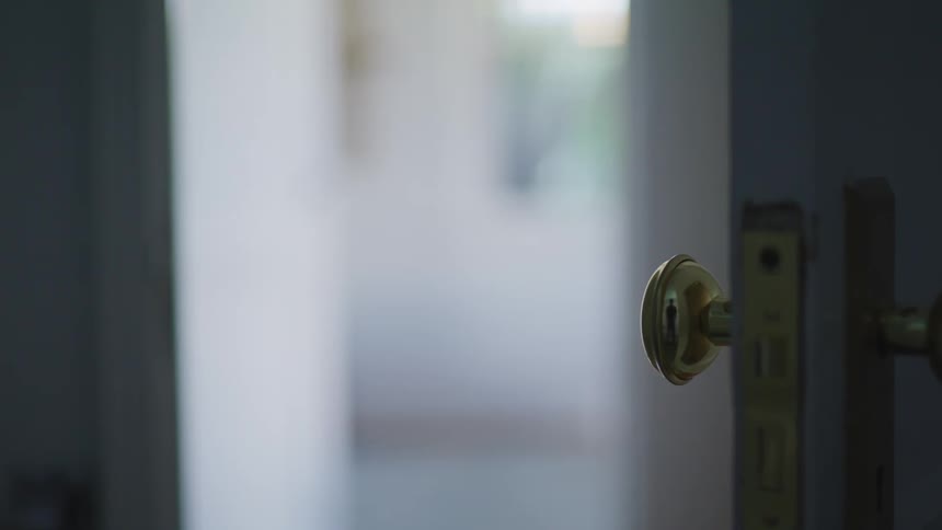 A gold doorknob on an open door indoors