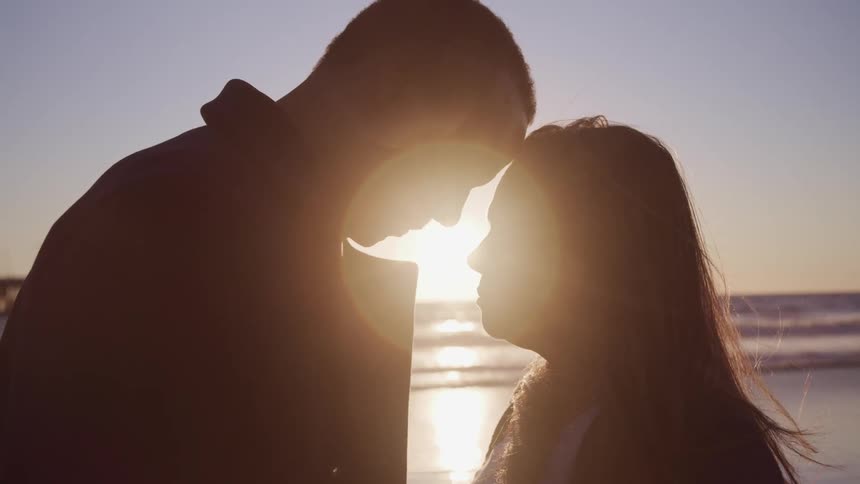 A man and woman on a beach put their heads together