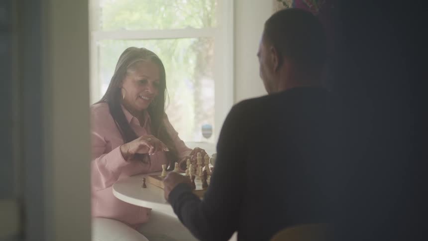 A man and woman sit at a table together playing chess