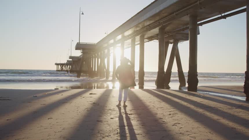 A female standing on the beach looking at the horizon