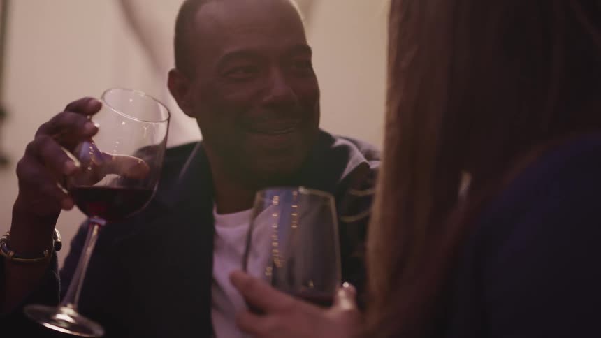 A man and a woman sitting and talking holding glasses of wine