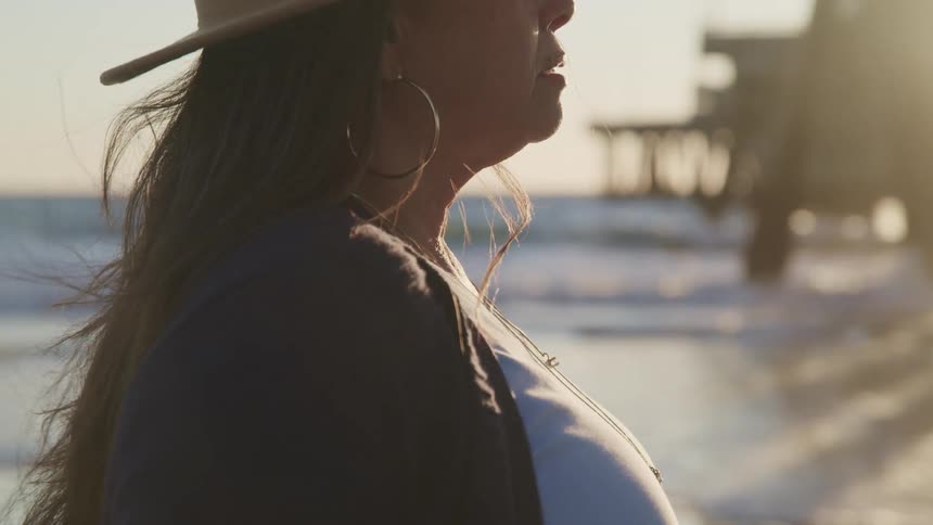 A woman looks down the beach as she stands on the shore