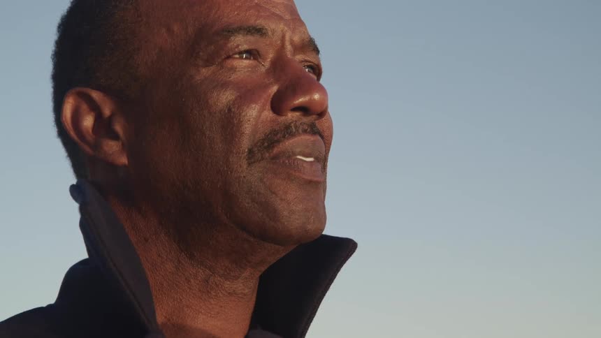 Side view of a black man with a mustache watching sunset