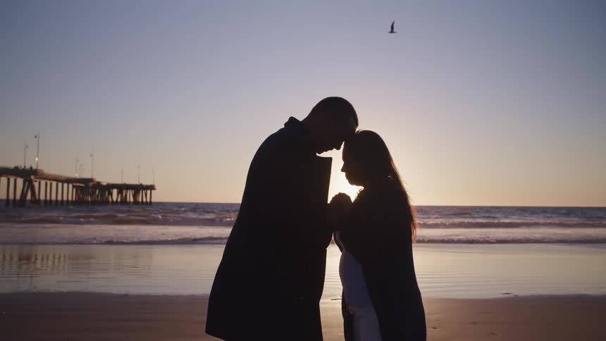A man and woman hold hands on the beach