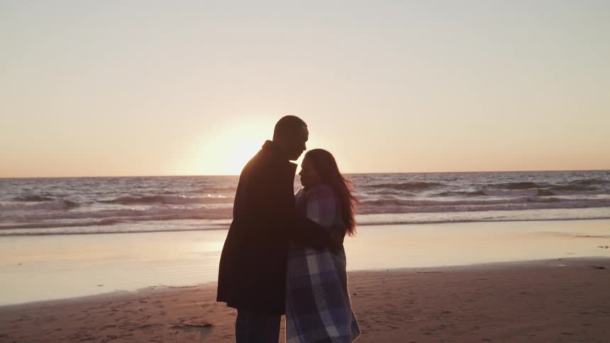 A husband and wife are hugging at the beach