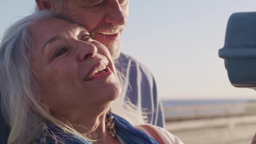 A man and woman laughing and hugging on the beach