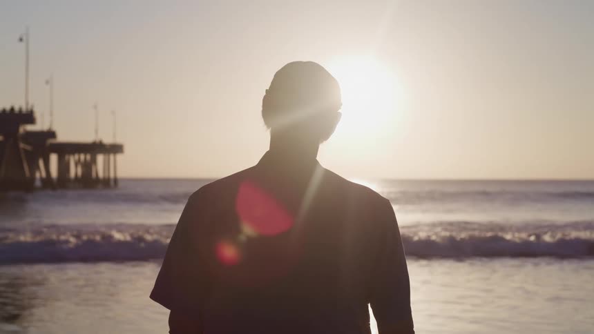 A man standing on the beach looking out at the water