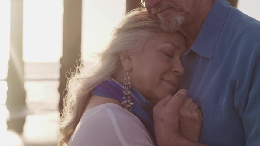 A man and woman dancing closely on the beach