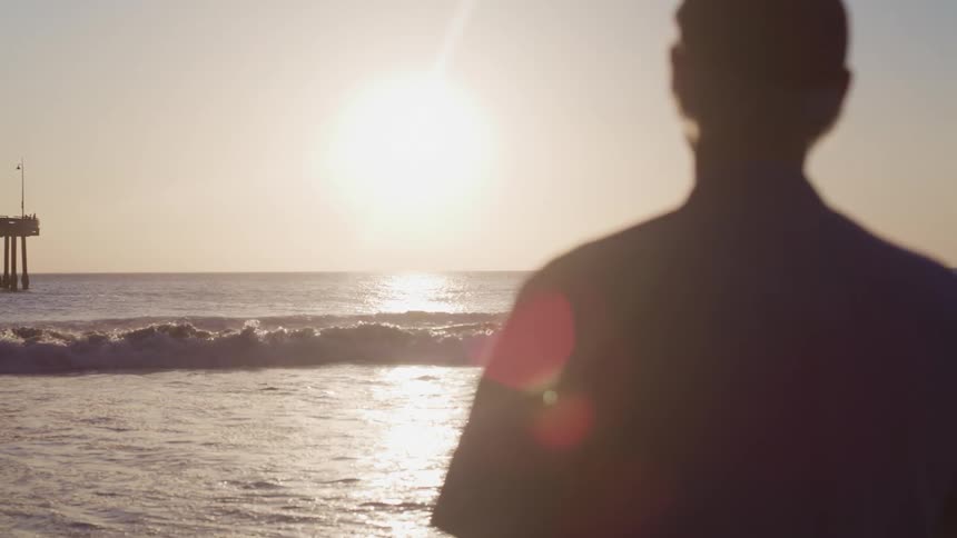 A man standing on the beach watching the waves roll in