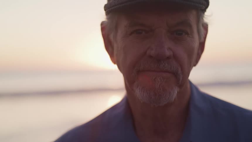 A man is standing on the beach at sunrise