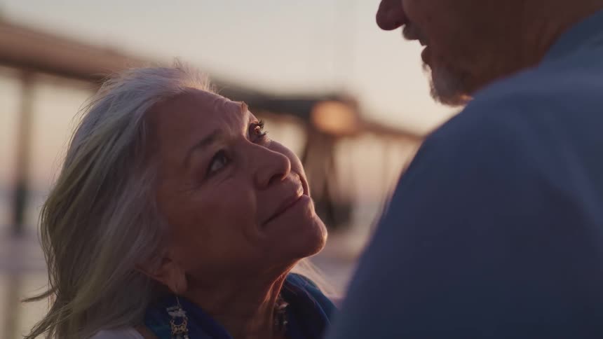 A man and woman on the shore look in to one anothers eyes