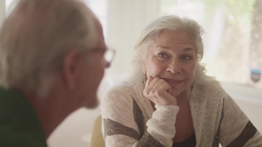 An elderly couple sitting at home talking