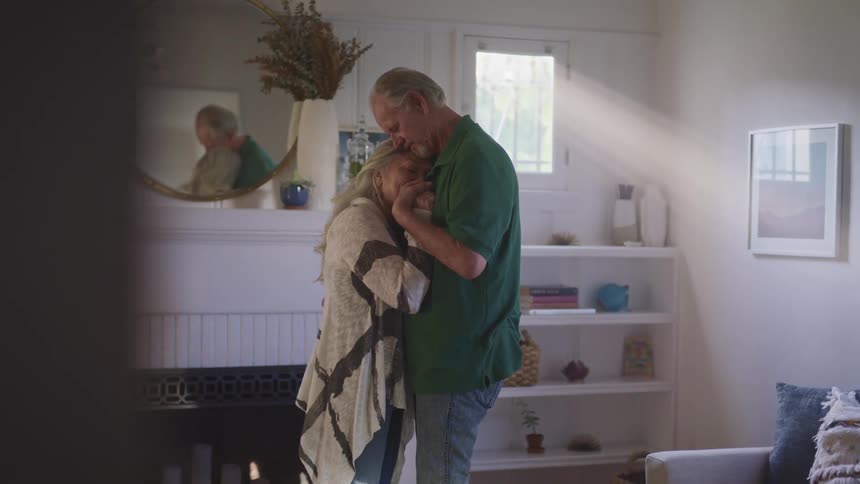 A man and woman dance in the living room