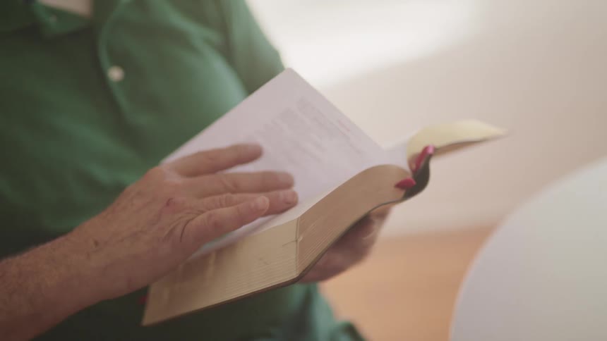 An man turns the page of a book he is holding
