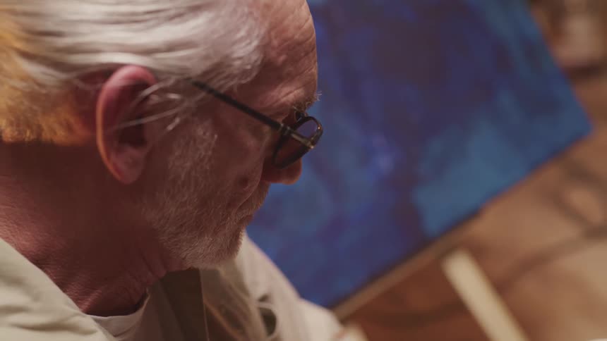 An elderly man is sitting indoors
