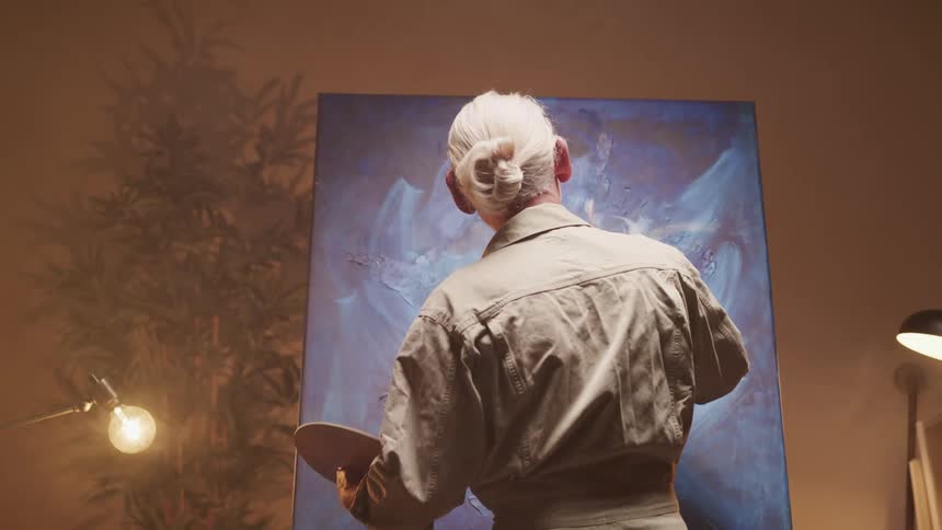 A person painting on a canvas indoors