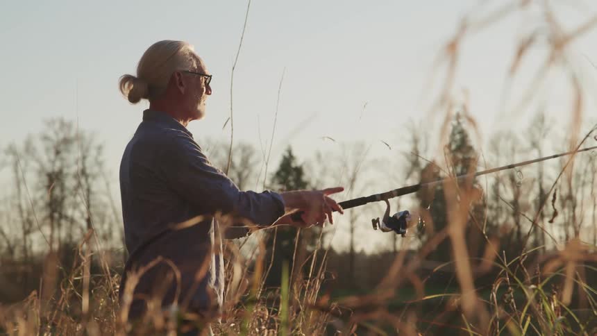 An aging fisherman swings his fishing pole to cast his fishing line