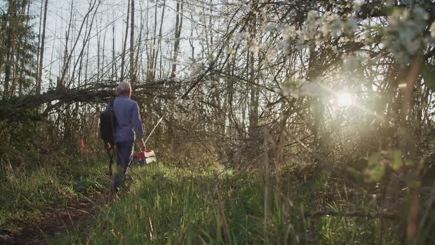 Walking through the forest carrying fishing gear on a sunny day