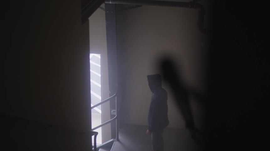 A man is standing still in the dark stairwell