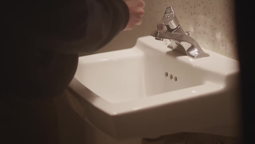 A person drops some pills by the sink