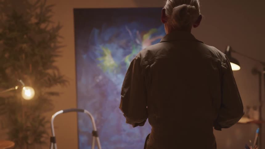 An elderly man is painting indoors