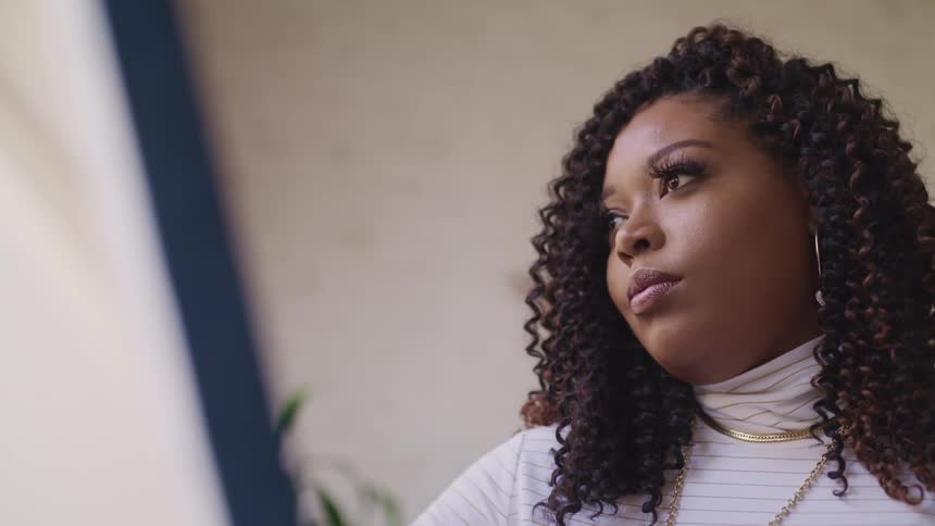 Side view of a chubby black woman with curly hair and earrings looking into space