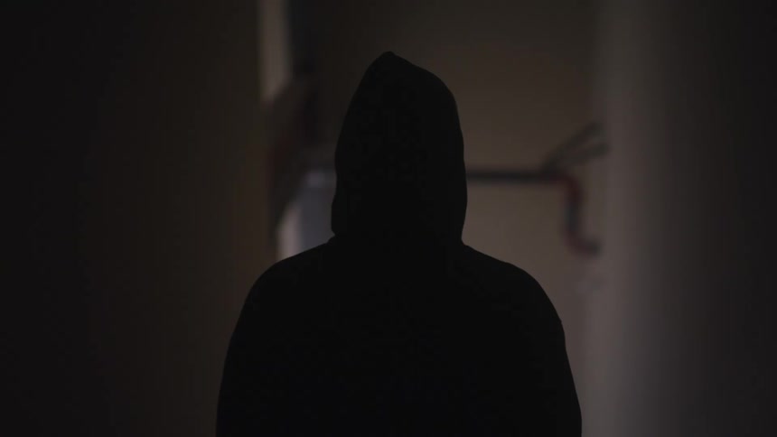 A person in a hoodie standing in a hallway