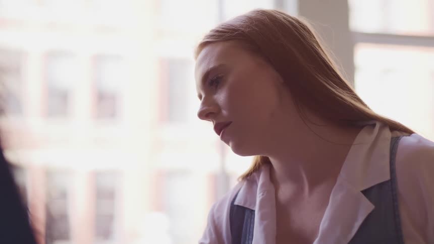 Side view of a woman with fair skin and red hair in a room