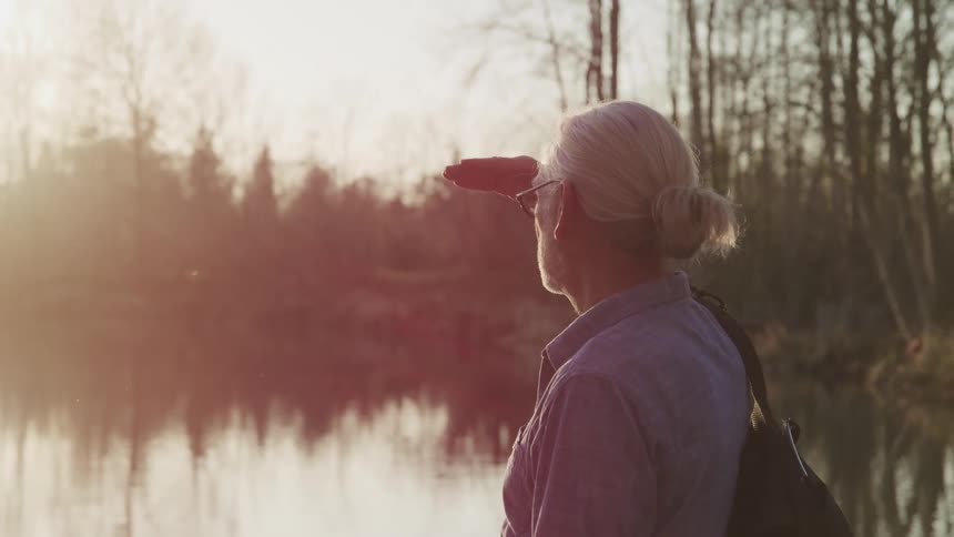 An elderly man is hiking outdoors at dawn