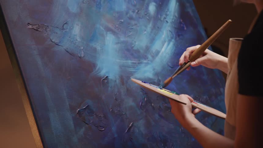 A woman painting on a large canvas