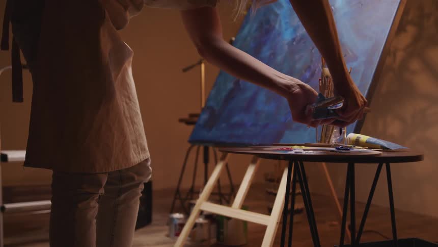 A woman squeezes paint on to a palette