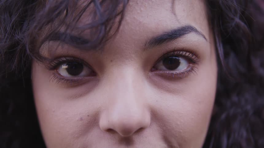 Woman with black curly hair stares at the camera
