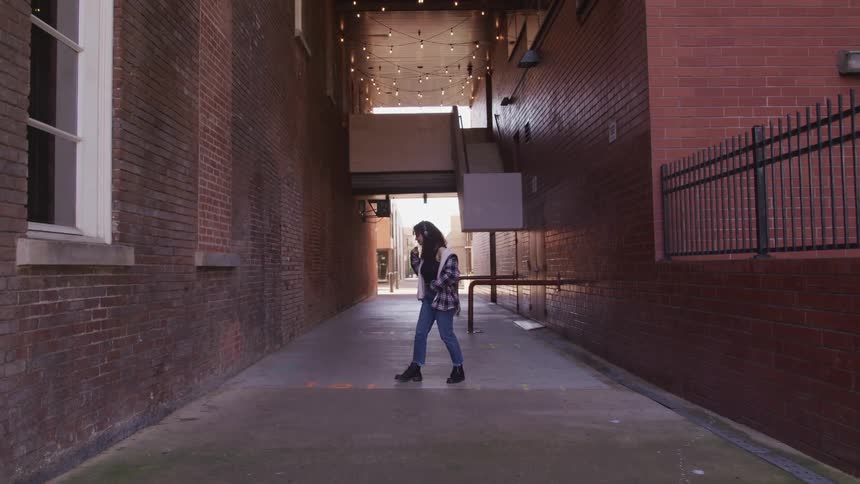 A teenage girl dancing as he listens to music in a corridor outside