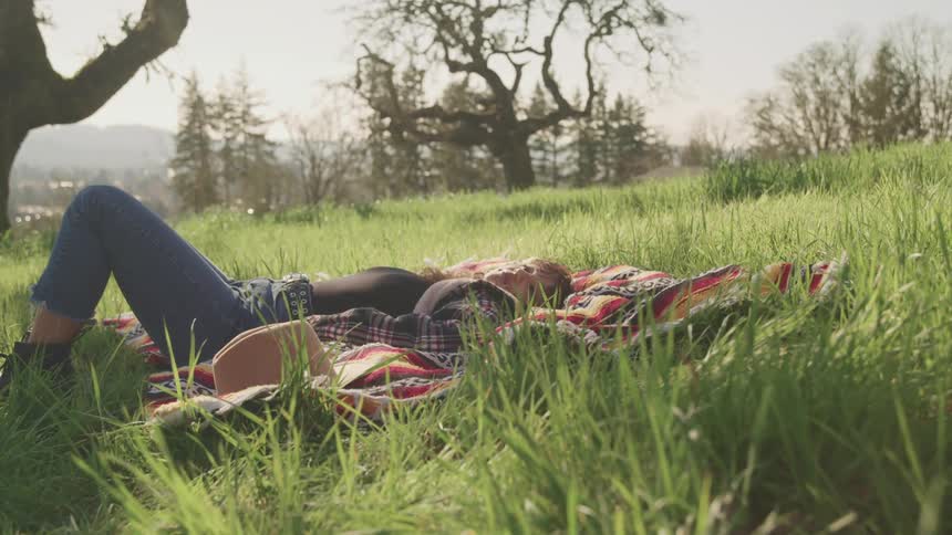 A woman is resting on the picnic blanket