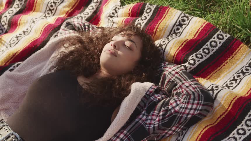 A woman is laying on a blanket outdoors