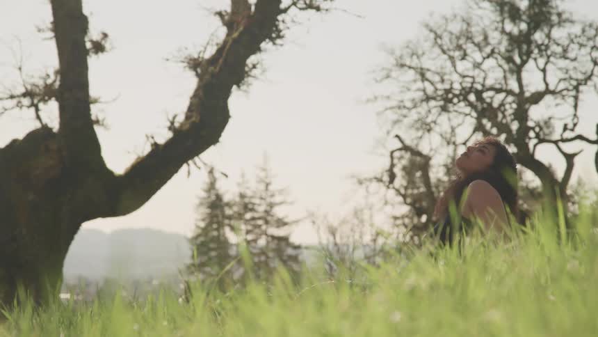 A female caucasian sitting on the grass in the sun