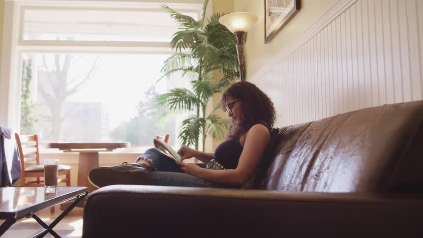 Woman sitting in a couch draws with her fingers on a note book