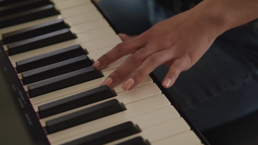 Woman with jeans presses piano keys