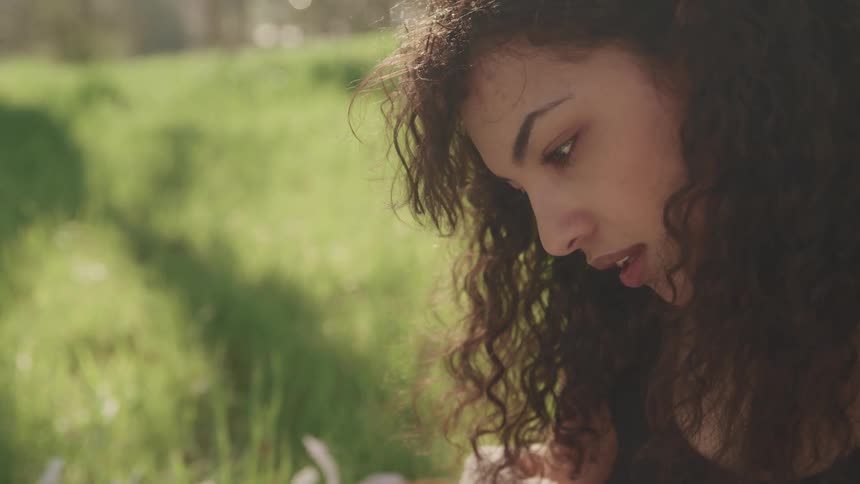 A woman is sitting in the grass outdoors